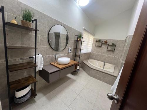 Un baño con lavabo, bañera y espejo. en Villa Guavaberry, en Juan Dolio