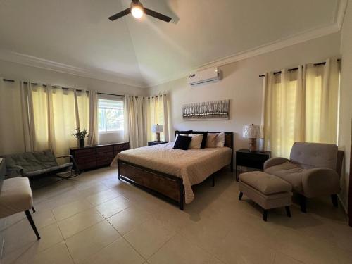 Un dormitorio con una cama, un sofá y una silla. en Villa Guavaberry, en Juan Dolio