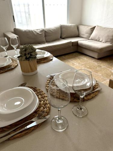 a table with plates and wine glasses on a table at Privada cerca de playa con Jacuzzi, BBQ y Terraza in Cancún