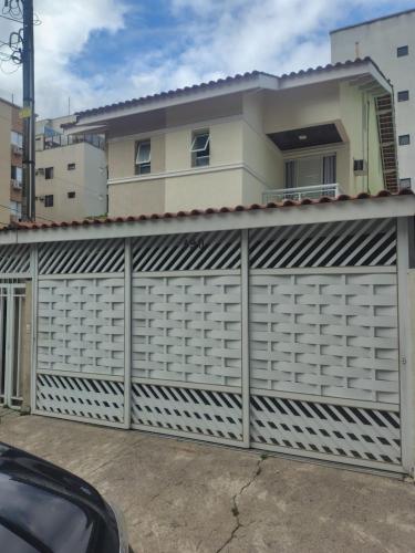 un garage avec une clôture blanche devant une maison dans l'établissement Casa 10 pessoas - praia das Astúrias, Guarujá, à Guarujá