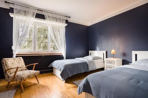 ein Schlafzimmer mit zwei Betten, einem Stuhl und einem Fenster in der Unterkunft La Rose in Schiltigheim