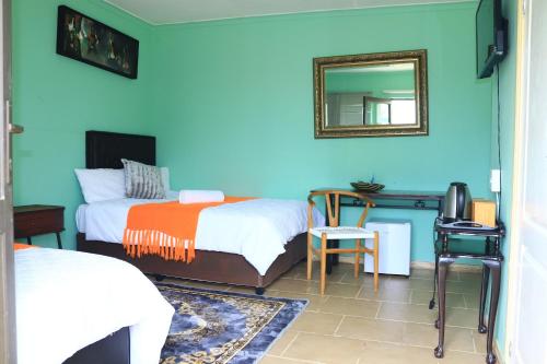 a bedroom with two beds and a desk with a mirror at Maison Royale Lodge in Nongoma