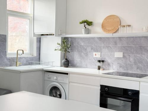 une cuisine blanche avec un évier et un lave-vaisselle dans l'établissement Modern 3-Bed House Near Attractions & Beach, à Blackpool