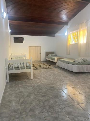 a room with three beds in it with a ceiling at Casa Gonzalez Oliveira in Mongaguá