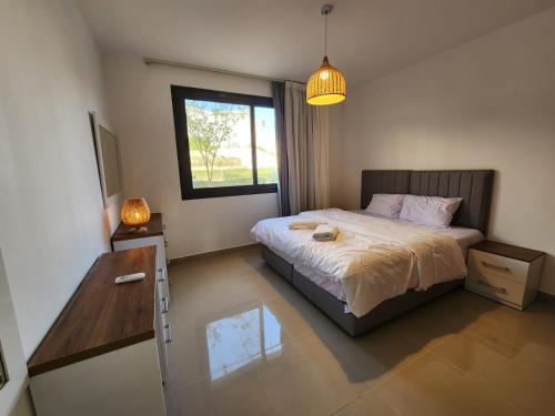 ein Schlafzimmer mit Bett, Schreibtisch und Fenster in der Unterkunft El Gouna Poolfront Cozy Stay 2BR in Hurghada