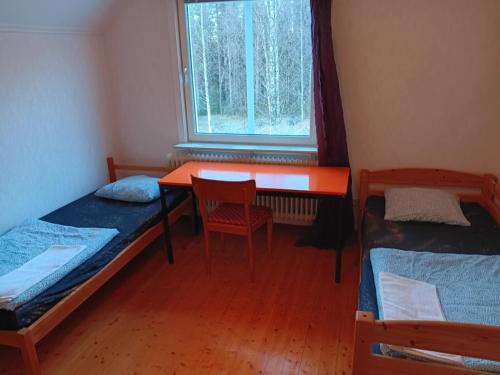 ein Zimmer mit zwei Betten und einem Schreibtisch und einem Fenster in der Unterkunft House in the middle of forests and lakes in Svartträsk