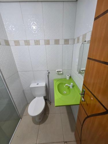 a bathroom with a toilet and a green sink at Eds pousada in Juazeiro do Norte