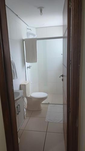 a white bathroom with a toilet and a sink at Praticita Apart Hotel Ltda in São Gabriel