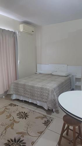 a bedroom with a bed and a table and a rug at Praticita Apart Hotel Ltda in São Gabriel