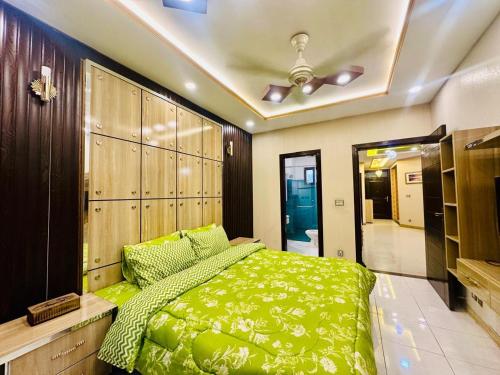 1 dormitorio con cama verde y techo en Grand apartments, en Lahore