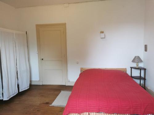 a bedroom with a red bed and a door at Grande maison de ville avec jardin Valence en Poitou pour 8 à 14 personnes in Couhé-Verac