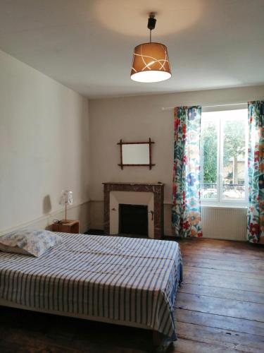 a bedroom with a bed with a fireplace and a window at Grande maison de ville avec jardin Valence en Poitou pour 8 à 14 personnes in Couhé-Verac