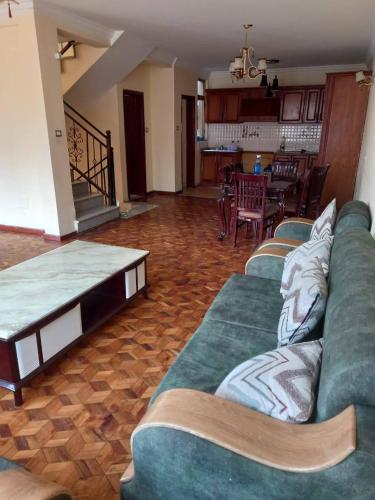 Una sala de estar con un sofá verde y una mesa. en Guest house, en Addis Ababa
