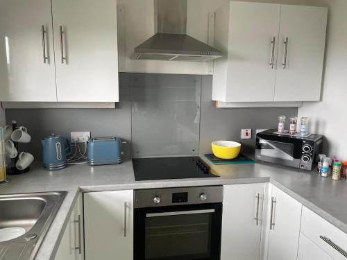 a kitchen with white cabinets and a stove top oven at Spacious two bedroom flat, entire property in Greenock