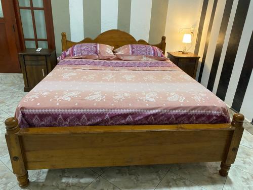 a wooden bed with pink sheets and pillows at Dona's Villa, Coastal Tropical House in Kepungoda