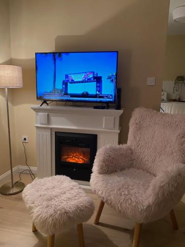 ein Wohnzimmer mit einem Kamin, einem TV und einem Stuhl in der Unterkunft Bonne Vie Cottage - Zebegény in Zebegény