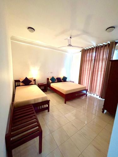 ein Zimmer mit zwei Betten und einem Fenster in der Unterkunft French Residence Tangalle in Tangalle