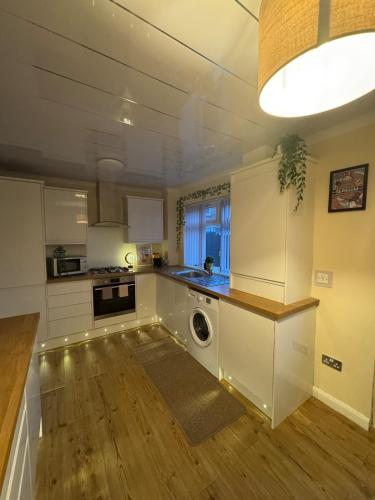 a kitchen with white cabinets and a washer and dryer at Cosy Glasgow Barrowlands stay-spacious & free parking in Glasgow