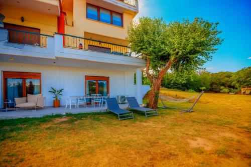 a house with chairs and a tree in the yard at Oasis Acropolis Serres With Parking Next to Center in Serres