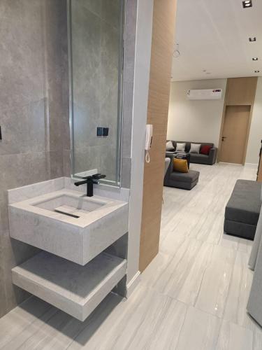 a bathroom with a sink and a living room at شاليهات أجواء الريف in Dammam