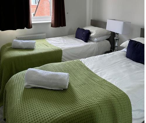 a room with three beds with green and white sheets at Margam's Gloucester House for Business Travellers in Cheltenham