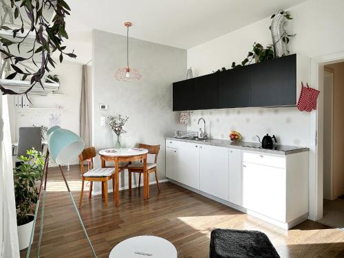 une cuisine avec des armoires blanches et une table dans une pièce dans l'établissement FRENCHCORNER apartment, à Brno