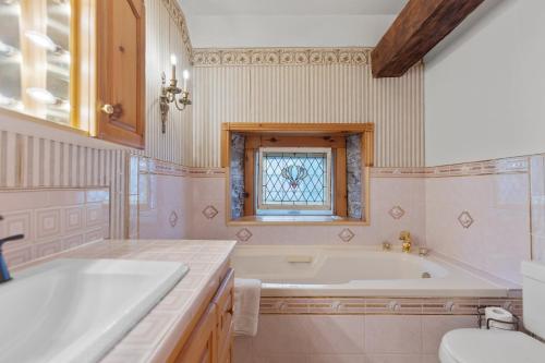 een badkamer met een bad, een wastafel en een raam bij Noble Suites in Brockville