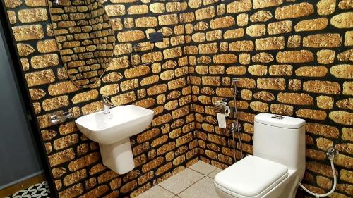 une salle de bains avec lavabo et toilettes et un mur en pierre dans l'établissement Goan Cozy 2 Bedroom Abode, à Calangute