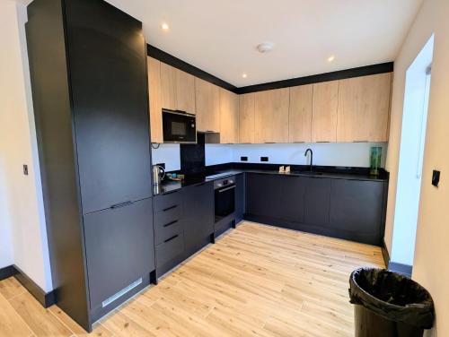 cocina con armarios negros y suelo de madera en Elegant 2 bed flat with balcony in London, en Finchley