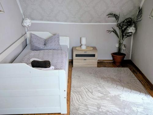 a bedroom with a white bed and a table with a plant at Töpferhäuschen Tangermünde in Tangermünde