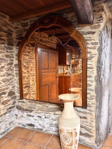 a vase in front of a stone wall with a mirror at Villa Tojo in Touro