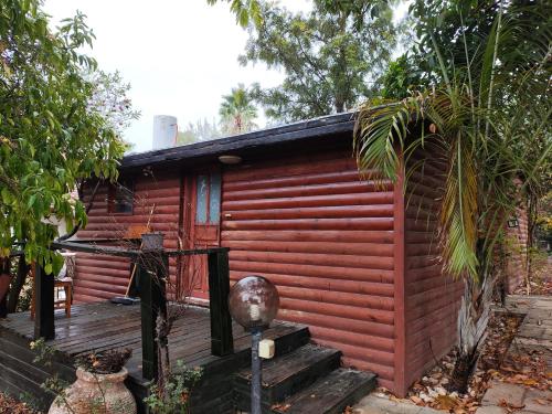 une petite cabine rouge avec une terrasse en bois dans l'établissement galilpitality, à Sede Eli‘ezer