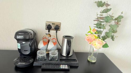 eine Kaffeemaschine auf einem Tisch neben einer Vase mit Blumen in der Unterkunft Armadillo Guest House- Adults Only in Edinburgh