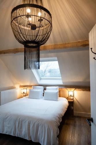 a bedroom with a large bed with a chandelier at B&B Langeveldemolen in Merchtem