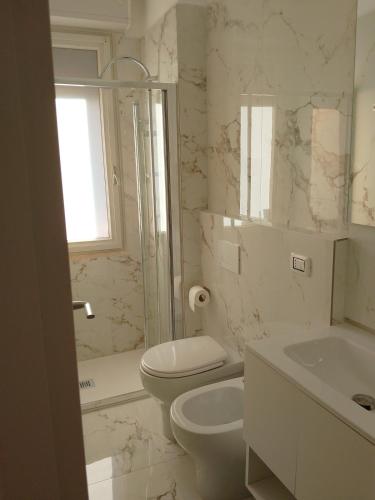 een witte badkamer met een toilet en een wastafel bij Il sorriso romagnolo in Misano Adriatico