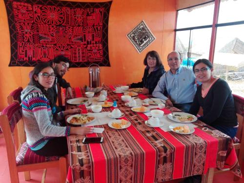 un groupe de personnes assises à une table en train de manger dans l'établissement Uros Titicaca Floating Bed, à Puno