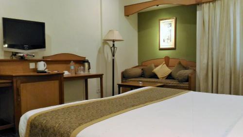 a hotel room with a bed and a television at Taj Tristar in Hyderabad