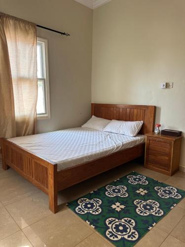 una camera da letto con un letto di legno con un tappeto di Izzy's Residence a Bijilo