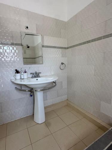 un bagno bianco con lavandino e specchio di Izzy's Residence a Bijilo