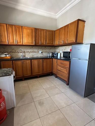 una cucina con mobili in legno e un frigorifero di Izzy's Residence a Bijilo