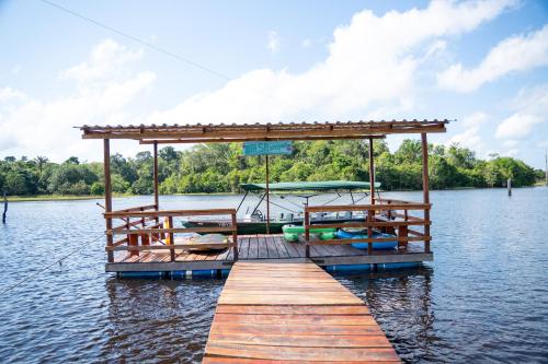 a wooden dock with a boat on the water at Ybyra Pousada de Selva in Careiro