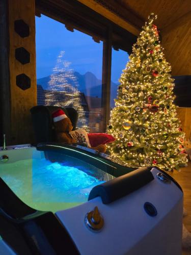 コシチェリスコにあるSobiczkowy Dwór Apartament -Kasprowy Wierch Premium DeLuxe & SPAのクリスマスツリーと、その隣の椅子に座っているテディベア