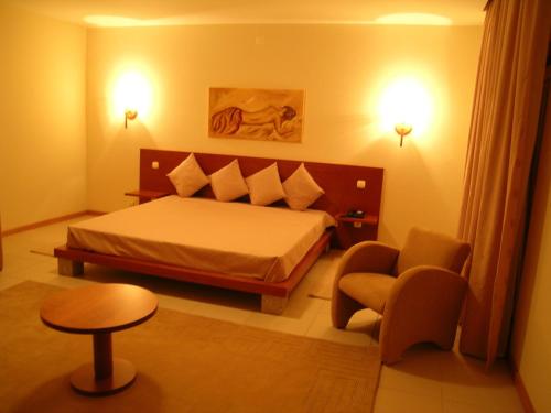 a bedroom with a bed and a chair and a table at Hotel Pombeira in Guarda