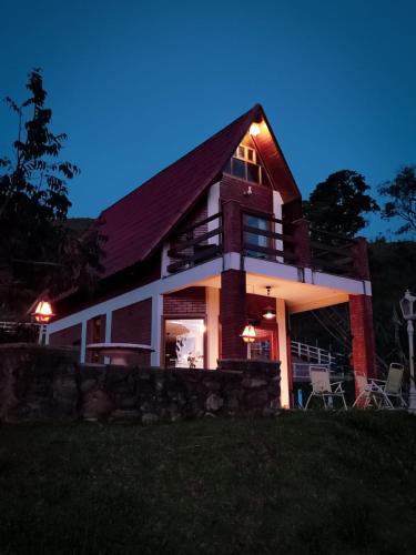 a house with lights on the side of it at night at Pousada Finca dos Anjos in Passa Quatro