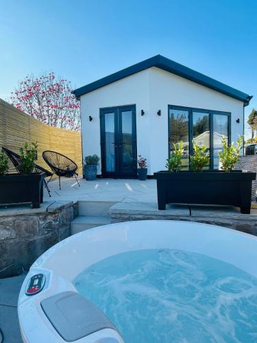 a large hot tub in front of a house at The Summer House - Tiny Home with Hot Tub in Coity