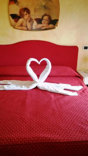 a white heart is on a red bed at Hotel Gioiella Depandance in Bellaria-Igea Marina
