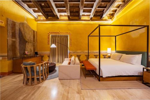 a bedroom with yellow walls and a bed and a chair at Casa Carolina Luxury Wellness Hotel in Cartagena de Indias