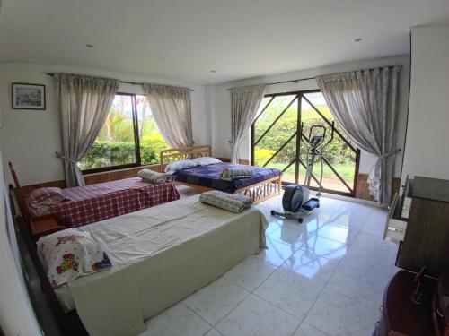 a bedroom with two beds and a large window at Villa campestre en conjunto residencial in Arbeláez