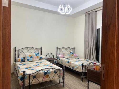 阿莱曼Ilatini New Alamein Lagoon View - الحي اللاتيني的一间有两张床和一盏枝形吊灯的卧室