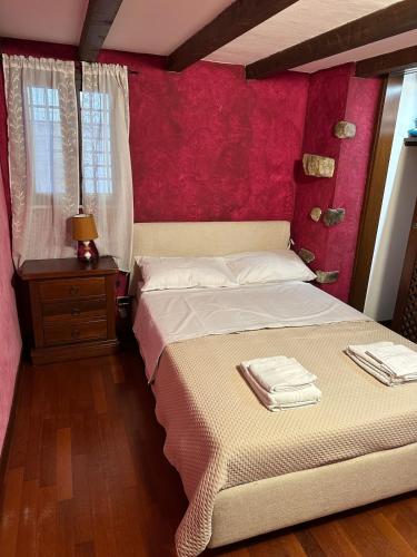 une chambre avec un lit avec un mur rouge dans l'établissement Charme Rustico 70 mt from the beach, starlink, à Cefalù